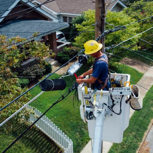 photography of man repairing electrical wires