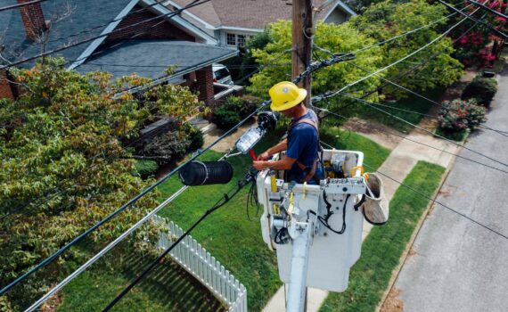 photography of man repairing electrical wires