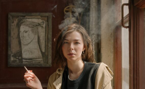 woman in black crew neck shirt and brown coat holding cigarette stick