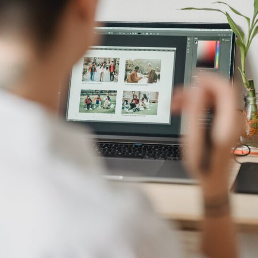woman sitting at table with laptop and editing photos