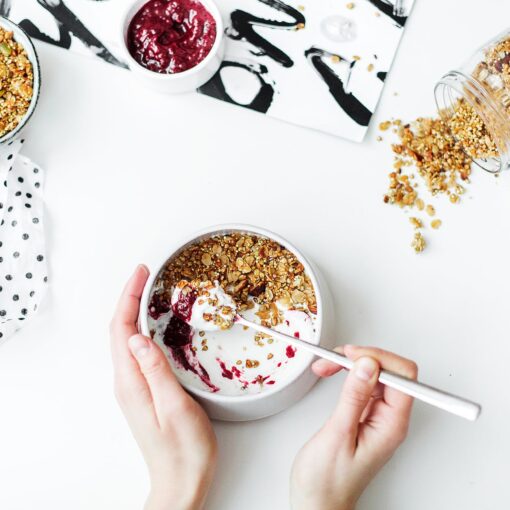 person mixing cereal milk and strawberry jam on white ceramic bowl