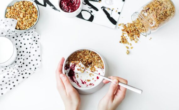 person mixing cereal milk and strawberry jam on white ceramic bowl