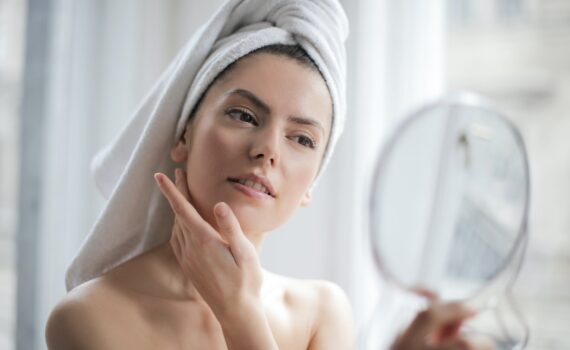 selective focus portrait photo of woman with a towel on head looking in the mirror