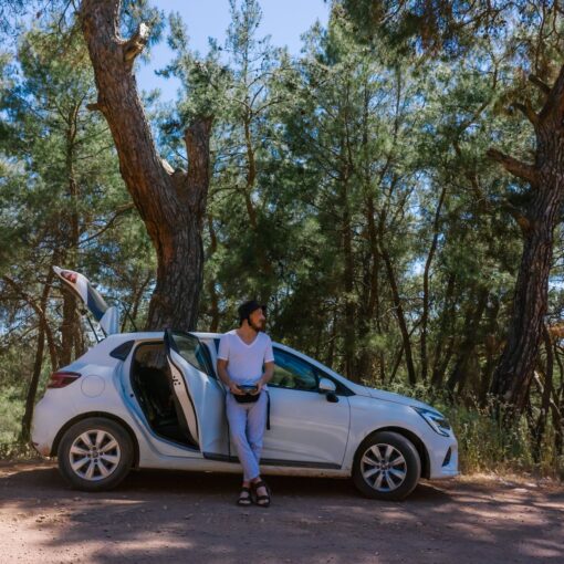 a man in white shirt standing beside white car