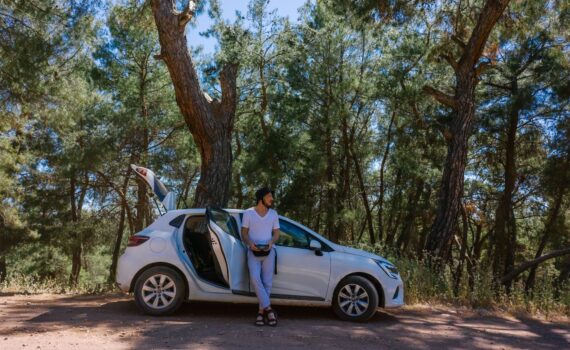a man in white shirt standing beside white car