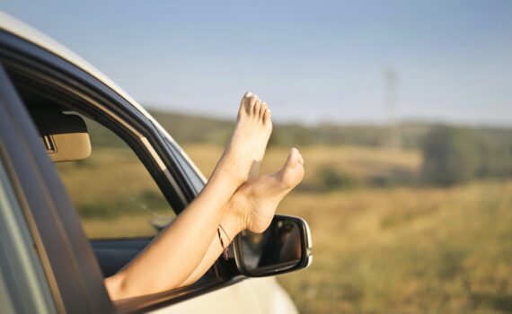 crop carefree woman with legs sticking out of car window
