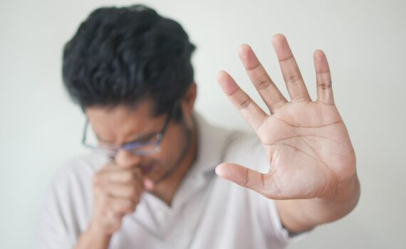 selective focus photo of coughing man s hand