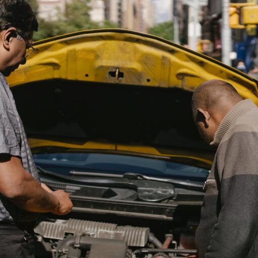 ethnic mechanic checking car standing near man