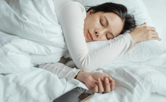 woman sleeping in bed near smartphone