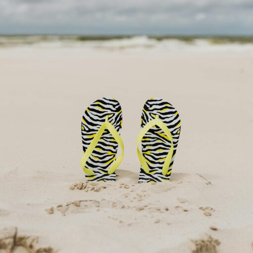 yellow strapped slippers buried on a sandy shore