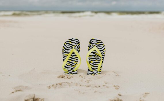 yellow strapped slippers buried on a sandy shore
