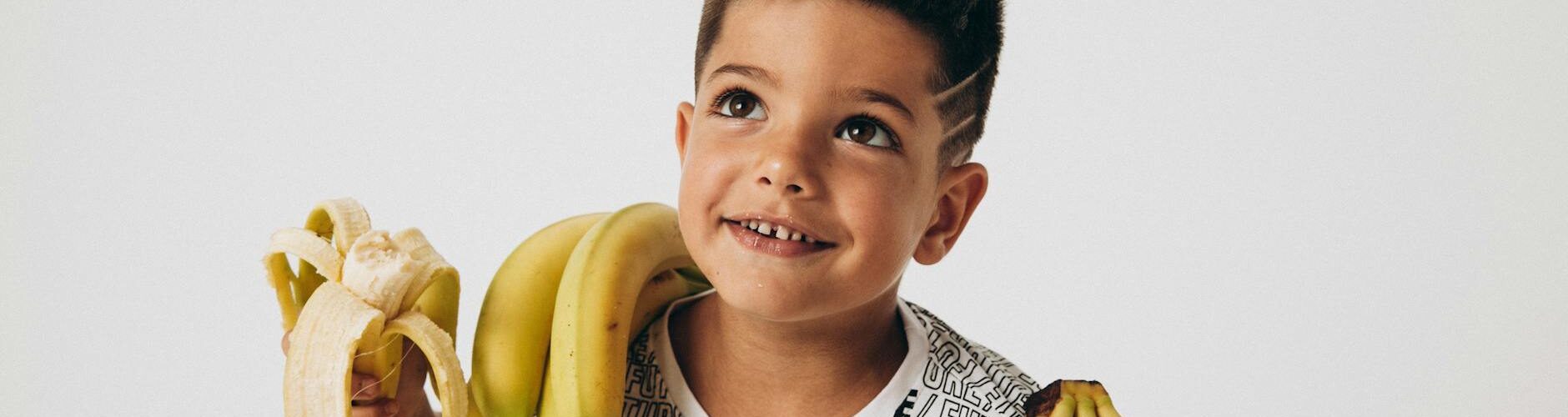 young boy holding a bunch of bananas