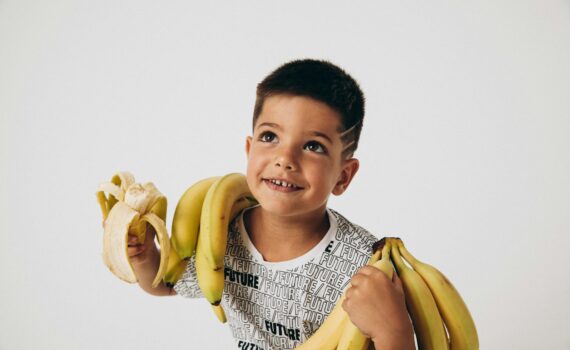 young boy holding a bunch of bananas